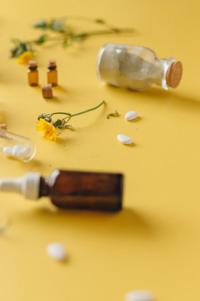 A flat lay of medicinal herbs, pills, and bottles on yellow background.